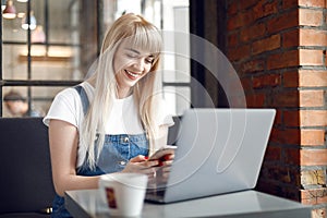 Young girl at cafe drinking coffee and using mobile phone. Online shopping