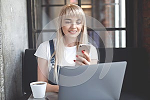 Young girl at cafe drinking coffee and using mobile phone. Online shopping