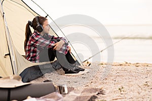 Young girl on camping trip.Child in a tent on beach listening music. Camping. Happy kid at summer vacations. travel