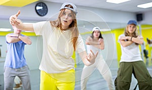 Young girl in cap training breakdance Toprock moves in dance hall