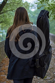 Young girl carry guitar bag while walking alone in naure