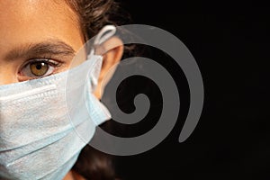 Young girl child with medical mask wearing, protection against covid 19 or coronavirus pandemic on black background with