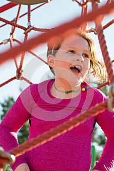 Young girl child playing at outdoor playground climbing net