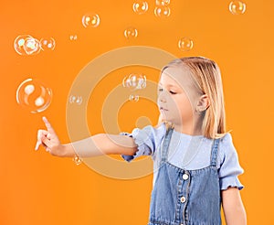 Young girl child, pop bubbles and game, playing and fun with youth isolated on orange background. Liquid soap