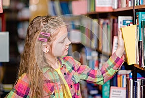 Young girl chooses a book in the library