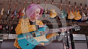 Young girl chooses a electric guitar in a music store, can't decide