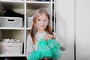Young girl choosing dress in wardrobe at home. The wardrobe which put in order. All things are folded neatly. Many boxes. Everythi