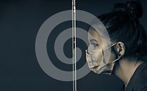Young girl with a clear respirator behind a safety window