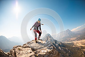 young girl climber in a helmet and with a backpack walks along a mountain range against the backdrop of mountains and climbing and