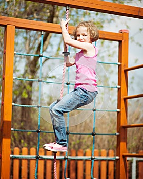 Young girl climbing rope in playground