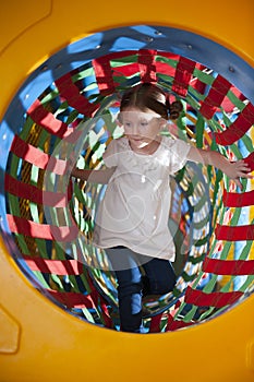 Young girl climbs through netted tunnel in soft play centre