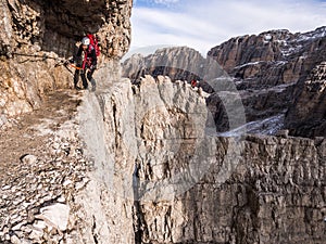Young girl climbs via ferrata high in the mountains photo