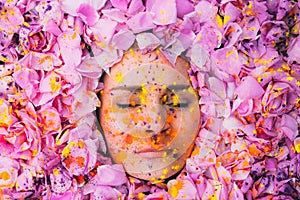 Young girl with closed eyes among the pink petals of rose