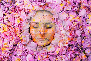 Young girl with closed eyes among the pink petals of rose