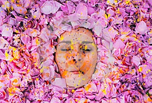 Young girl with closed eyes among the pink petals of rose