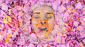 Young girl with closed eyes among the pink petals of rose, tongue out