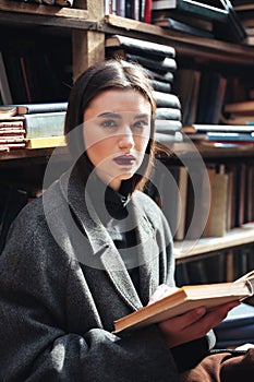 Young girl in coat holding book in an old library