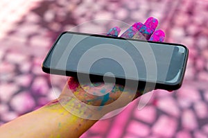 Young girl with colored gulaal powder on her hands holding a mobile phone during the festival of holi photo