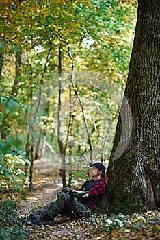 Young girl with colored hair sits in the forest