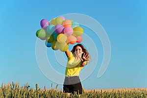 Young girl with colorful balloons in sunset meadow