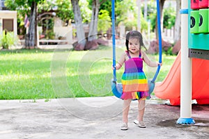 Young girl in colorful dress was playing on blue swing and was tired and sweat wet her hair.