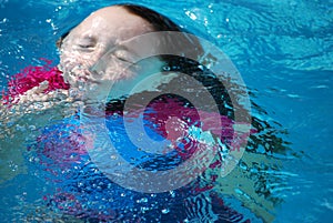 Young girl coming up from underwater in a pool.