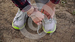 Young girl commits an outdoor walk and stopped to tie his shoelaces on sneakers