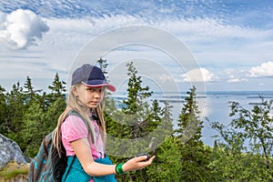 Young girl with compass on the hill top in Koli National Park