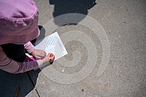 Young girl completing a zoo scavenger hunt form outdoors in the spring.