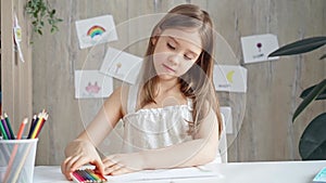 Young girl concentrating on drawing at the desk at home or school class room