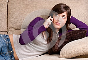 Young girl concerned talking by telephone bad news lying on couch