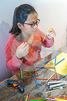 A young girl is constructing with lots of colorful plastic sticks. fun with building geometric figures and learning mathematics at