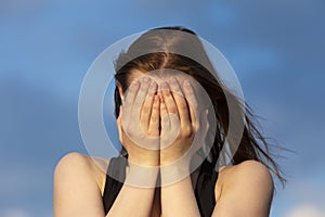 Young girl covering face with hands while crying. Depression concept.