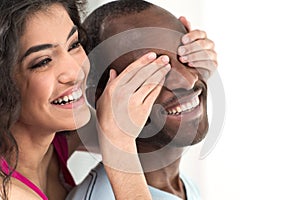 Young girl covering her boyfriend eyes with both hands.