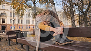 A young girl crying on a park bench in the fall.