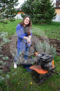 Young girl with a cultivator in the field plowing land