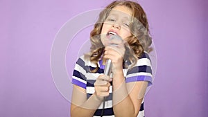Young girl with curly hair holding microphone, singing and funy dancing