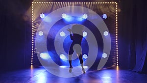 Young girl dancing jazz funk in the studio in slow motion. Silhouette against the background of blue lights.