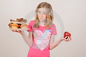 Young girl deciding junk food or apple photo