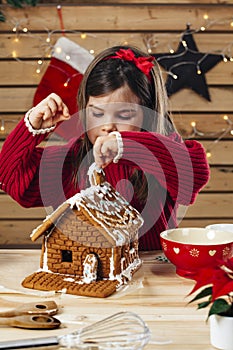 Young girl decorating gingerbread house