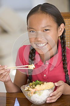 Young girl in dining room eating Chinese food