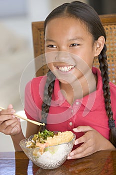 Young girl in dining room eating Chinese food