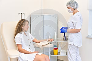 Young girl at a doctor`s office appointment. woman gives blood. doctor in mask and gloves