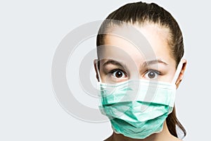 Young girl in doctors mask looking surprised and shocked