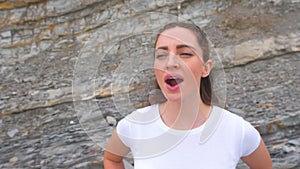 Young girl does breathing exercises inhale and exhale of bodyflex. Classes body flex on the background of rocks. Face