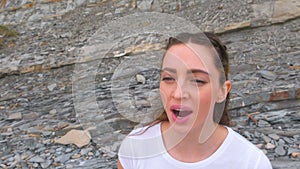 Young girl does breathing exercises inhale and exhale of bodyflex. Classes body flex on the background of rocks. Face