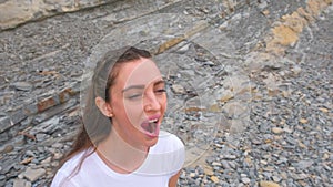 Young girl does breathing exercises inhale and exhale of bodyflex. Classes body flex on the background of rocks. Face