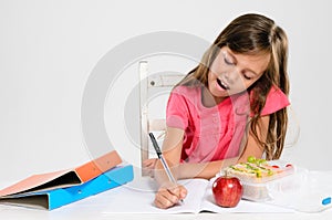 Young girl does her homework on table