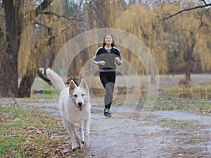 Young girl with dog running at the forest