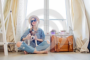 Young girl with dog sitting next to suitcase